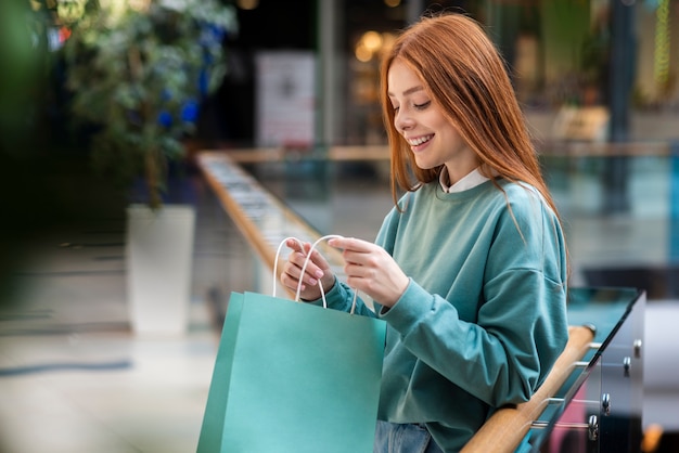 Mulher ruiva olhando para dentro da sacola de compras Foto gratuita
