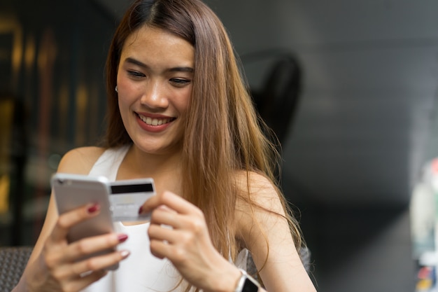 Mulher segurando o smartphone com cartão de crédito para pagar o conceito de comércio eletrônico de compras on-line Foto Premium