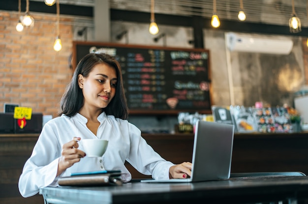 Mulher sentada e trabalhando com um laptop em uma cafeteria Foto gratuita