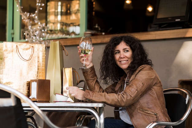 Mulher, sentando, com, bolsas para compras, e, vinho Foto gratuita