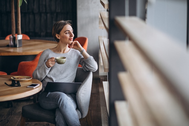 Mulher, sentando, em, um, café, café bebendo, e, trabalhar, um computador Foto gratuita