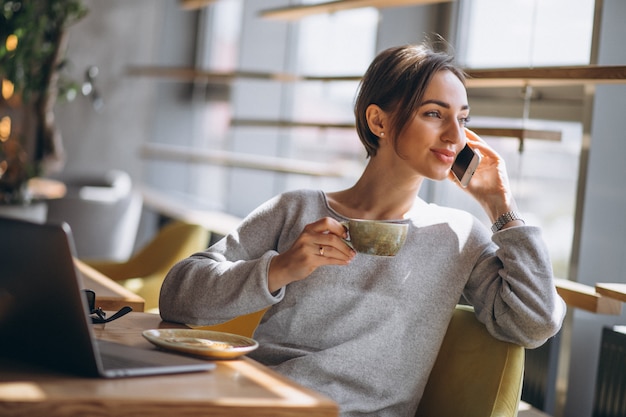 Mulher, sentando, em, um, café, café bebendo, e, trabalhar, um computador Foto gratuita