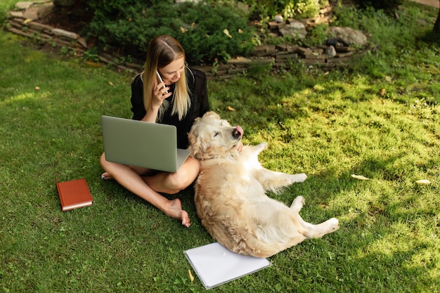 Mulher trabalhando com laptop e brincando com o cachorro labrador