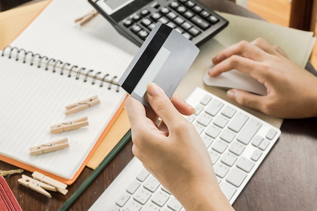 Mulher usando o computador para fazer compras on-line e pagar com cartão de crédito, pouca luz, foco seletivo na mão Foto Premium