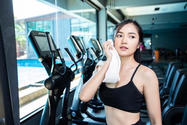 Mulheres após o exercício, limpe o rosto com um pano branco na academia. Foto gratuita