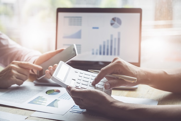 Negócio e parceria que discutem usando a calculadora para rever o anuário do balanço patrimonial com pena de terra arrendada e usar o laptop ao orçamento calculador. integridade de auditoria antes do conceito de investimento. Foto Premium