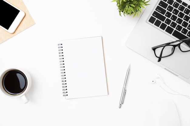 Notebook com a página em branco é no meio da mesa de mesa de escritório branco com suprimentos. Foto Premium