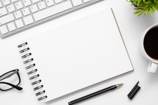 O caderno vazio está sobre a tabela branca moderna da mesa de escritório com fontes. vista superior com espaço da cópia, configuração lisa. Foto Premium