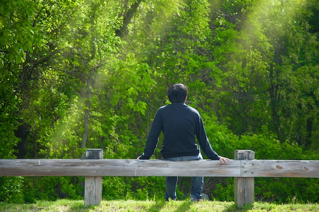 O homem está relaxando em uma madeira e curtindo a natureza | Foto Premium