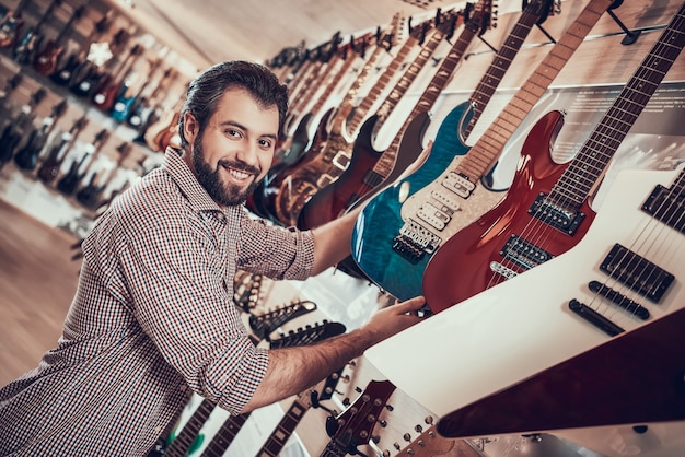 O músico farpado adulto compra a guitarra elétrica na loja da música. Foto Premium