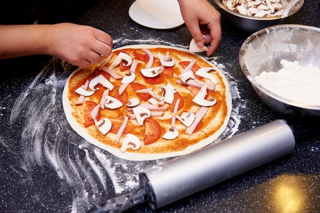 O processo de cozinhar pizza com carne, cogumelos, tomate e queijo. Foto Premium
