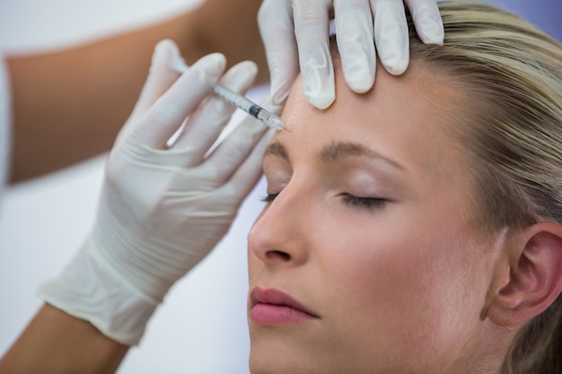 Paciente do sexo feminino recebendo uma injeção de botox na testa Foto gratuita