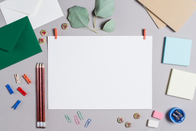 Página em branco em branco com cabide cercado com artigos de papelaria em fundo cinza Foto gratuita