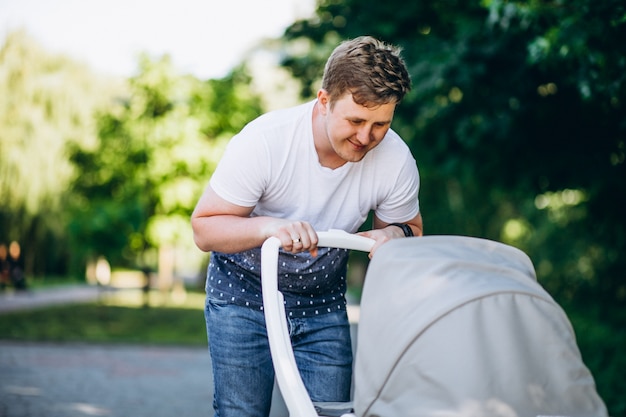 Pai andando com carrinho de bebê no parque Foto gratuita