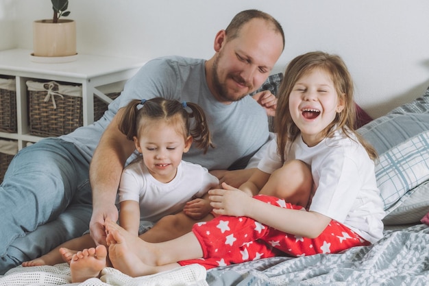 Pai Brinca Com Duas Crianças Na Cama Papai Faz Cócegas Nos Pés Das Crianças Família Do Papai E