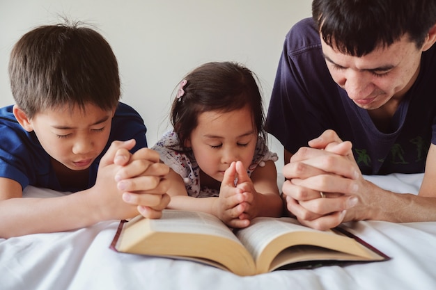 Pai e filhos rezando na cama, a família reza juntos | Foto Premium