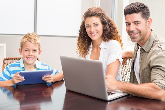 Pais felizes sentados com o filho usando tablet e laptop Foto Premium