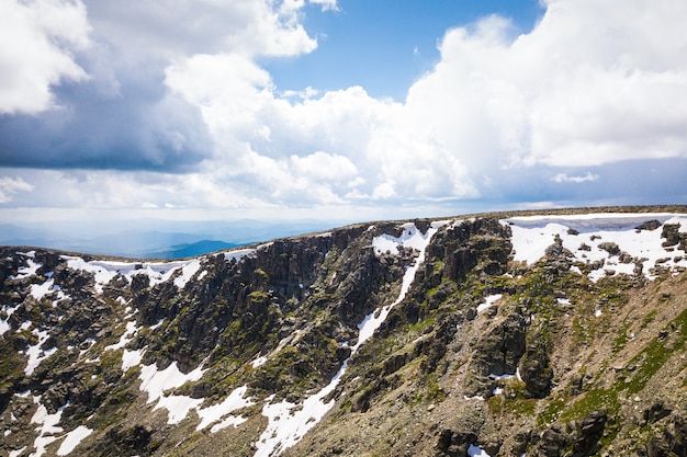 Panorama ultra largo do horizonte. montanhas cobertas de neve, clareira com uma floresta de coníferas verde contra o céu azul. Foto Premium