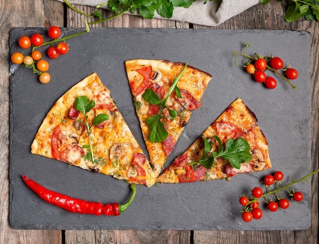 Pedaço triangular de pizza assada com cogumelos, linguiça defumada, tomate Foto Premium