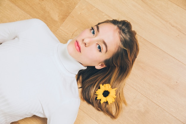 Pensativo, mulher, com, flor cabelo, mentindo chão Foto gratuita