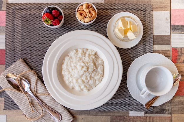 Pequeno-almoço saudável com tigela de mingau de arroz com frutas e nozes em cima da mesa Foto Premium