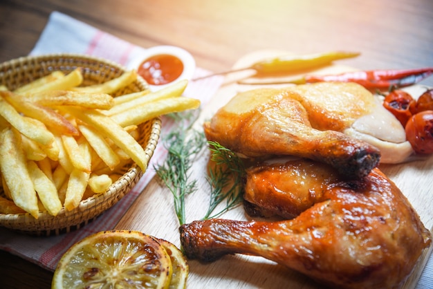 Pernas de frango assado na tábua de madeira e batatas fritas cesta com pimenta de limão de milho especiarias ervas picantes Foto Premium