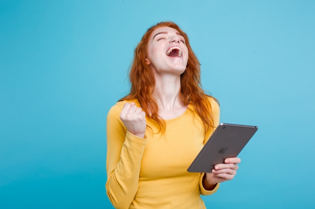 Pessoas e conceito de tecnologia - close up retrato jovem atraente atraente redhair menina feliz sorrindo na mesa digital com ganhar algo. fundo pastel azul. copie o espaço. Foto gratuita