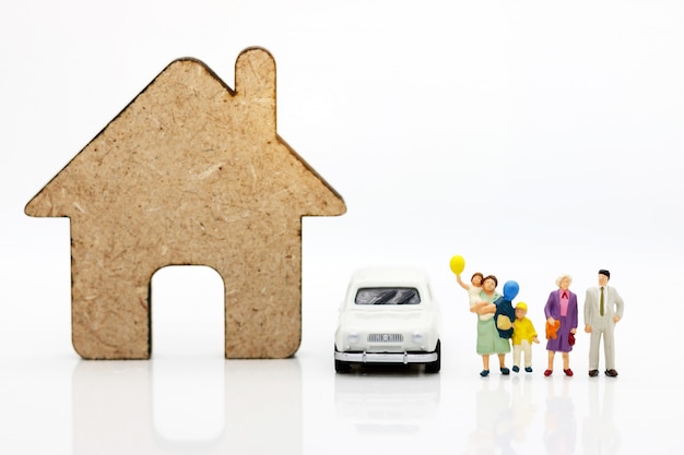 Pessoas em miniatura com a família em pé com casas e carros. Foto Premium