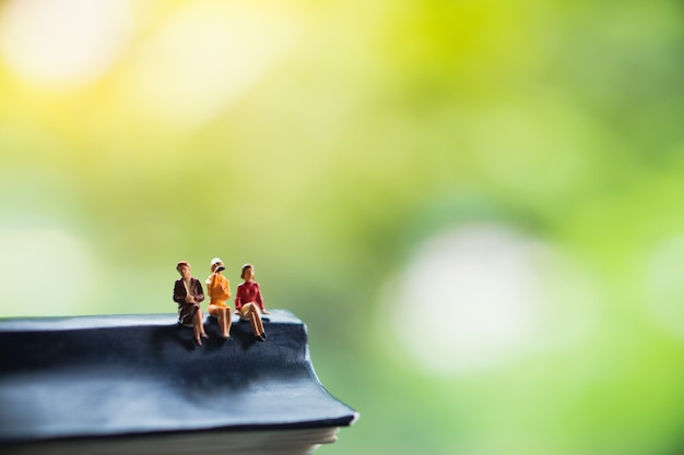 Pessoas em miniatura, mulher sentada no banco na natureza verde fundo usando para recursos humanos de negócios Foto Premium