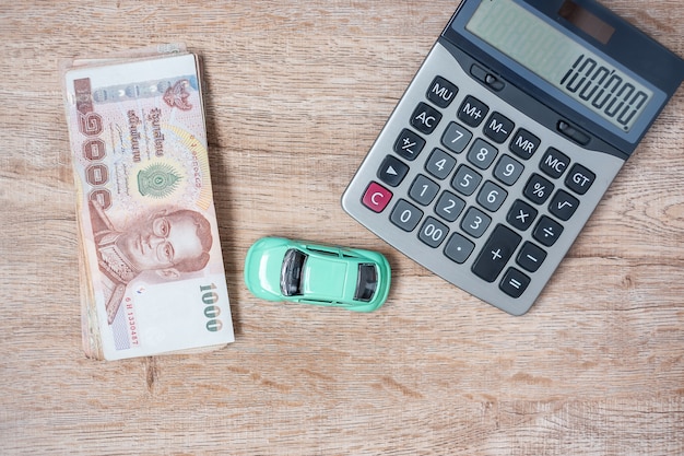 Pilha de cédulas do baht tailandês com carro e calculadora. Foto Premium