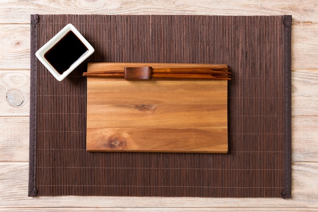 Placa de madeira vazia com os chopsticks para o molho do sushi e de soja na madeira. Foto Premium