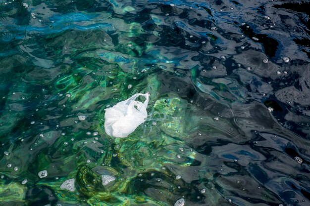 Plásticos e garrafas de plástico no mar com água muito limpa e cristalina Foto Premium