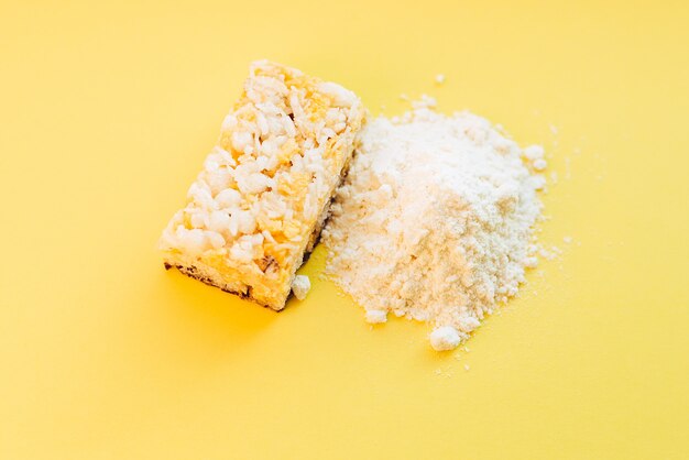 Pó de proteína de soro de leite e barra de proteína de cereais na parede amarela. Foto Premium