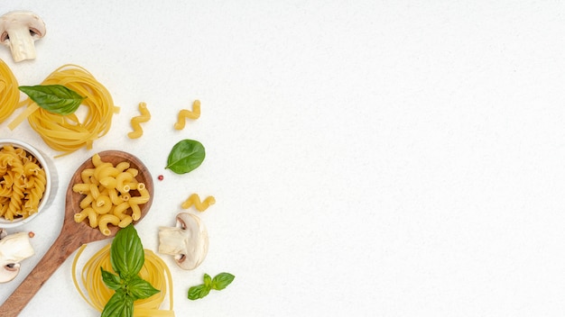 Postura plana de macarrão e colher de pau no fundo liso, com espaço de cópia Foto gratuita