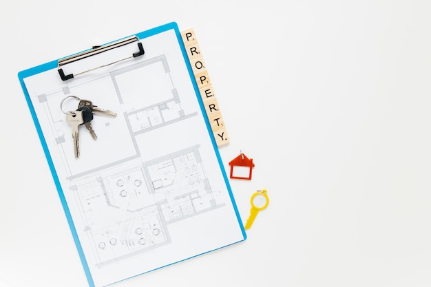 Prancheta do blueprint; chave de casa e bloco de propriedade com pano de fundo branco copyspace Foto gratuita