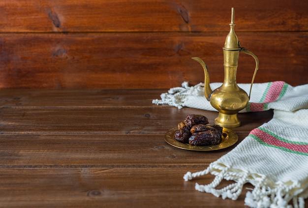 Preparação de alimentos do ramadã, bule de chá com datas, comida iftar em fundo de madeira com espaço de cópia Foto Premium