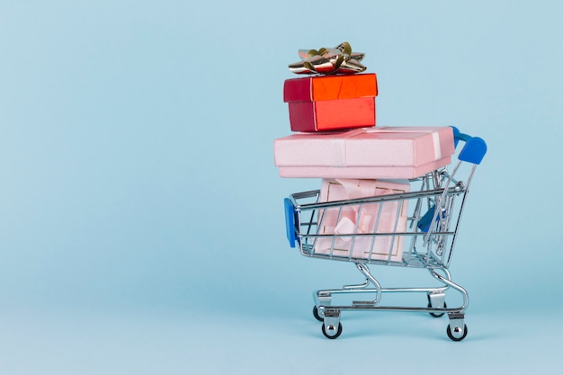 Presentes empilhados no cartão de compras na superfície azul Foto gratuita