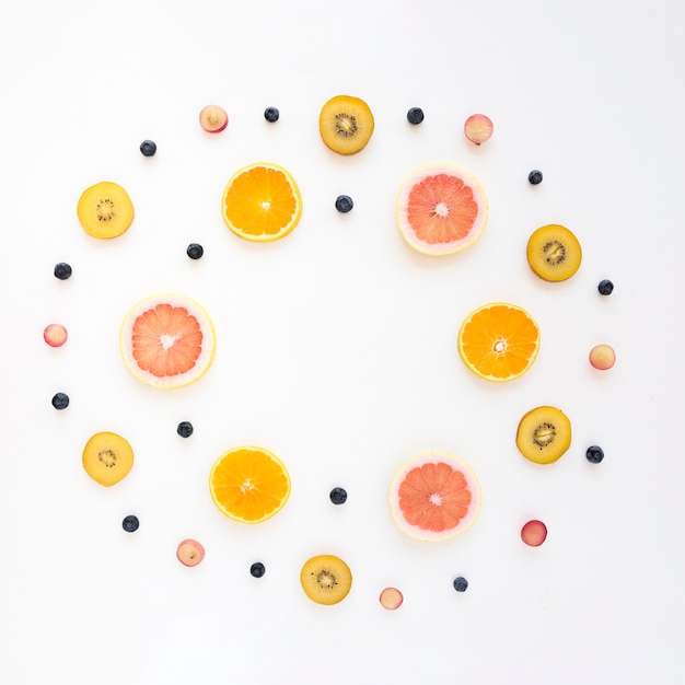 Quadro circular feito com laranja; uvas; kiwi; toranja e mirtilos em fundo branco Foto gratuita