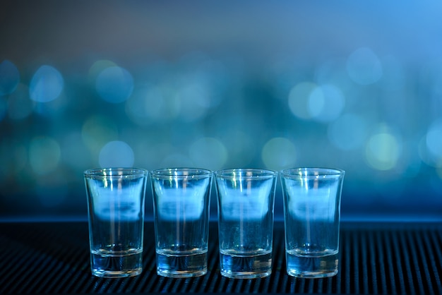 Quatro tiros de tequila em uma barra de mesa de madeira. Foto Premium