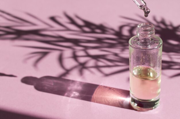 Queda cai de uma pipeta em uma garrafa de vidro com óleo cosmético ou soro Foto Premium