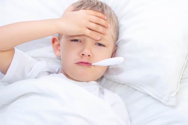Rapaz encontra-se na cama com um termômetro na boca. conceito de saúde ...