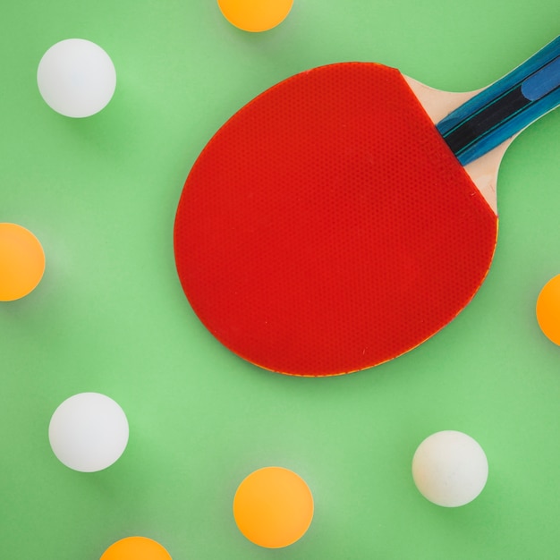 Raquete de ping-pong vermelho com bolas brancas e laranja em fundo verde Foto gratuita