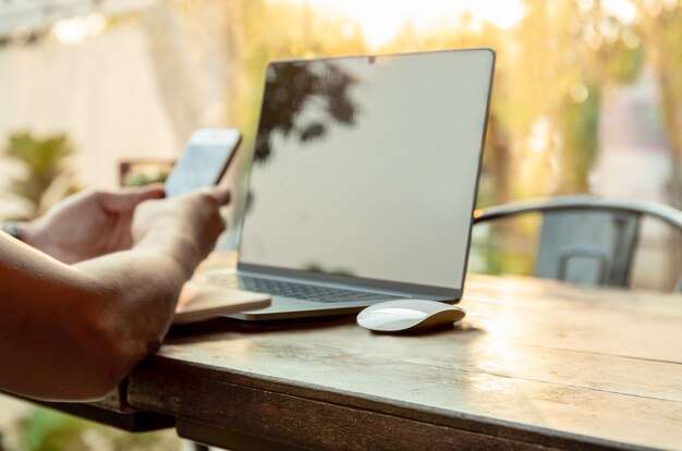 Rato selecionado do computador do foco com o homem que usa o telefone celular e o portátil na tabela. Foto Premium