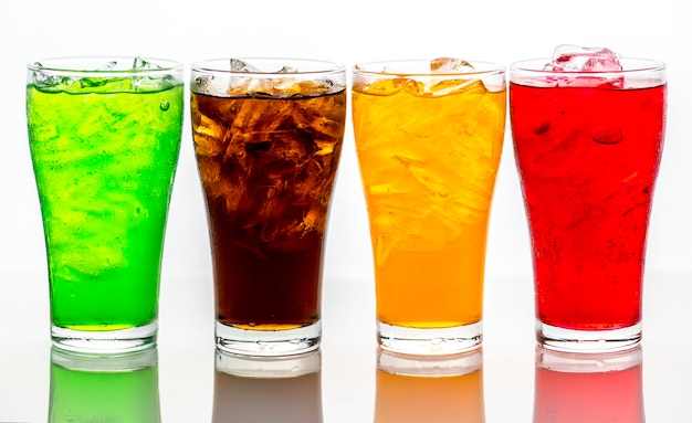 Quatro copos de refrigerantes coloridos com gelo em fundo branco