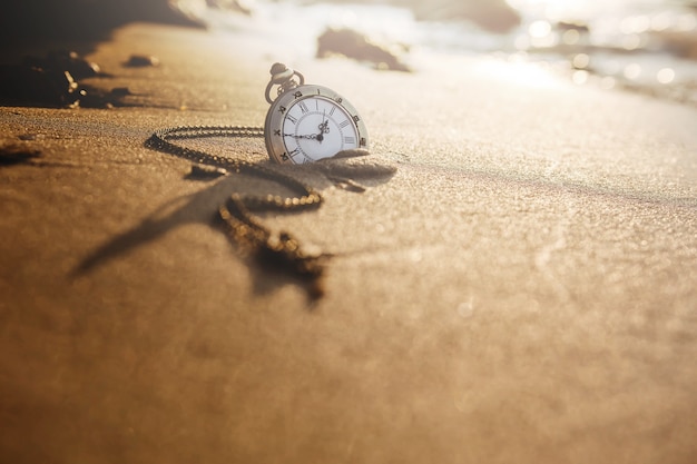 Relógio de bolso vintage na praia de areia dourada | Foto Premium