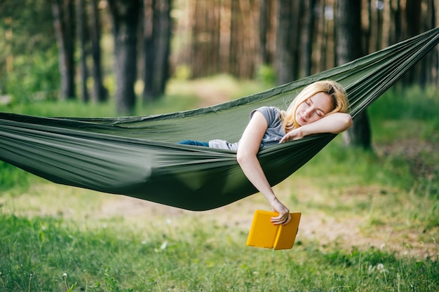 Retrato ao ar livre de jovem loira linda dormindo na rede na floresta de  verão ensolarado com e-book na mão. | Foto Premium