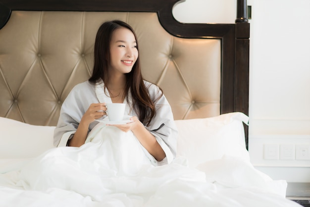 Retrato, bonito, jovem, mulher asian, acorde, com, feliz, sorrizo, e, xícara café, cama, em, quarto, inter Foto gratuita