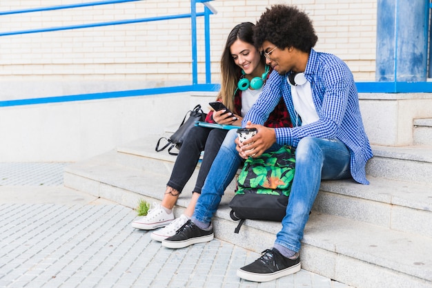 Retrato, de, diverso, adolescente, macho fêmea, estudantes, sentando, ligado, a, passos, usando, telefone móvel Foto gratuita