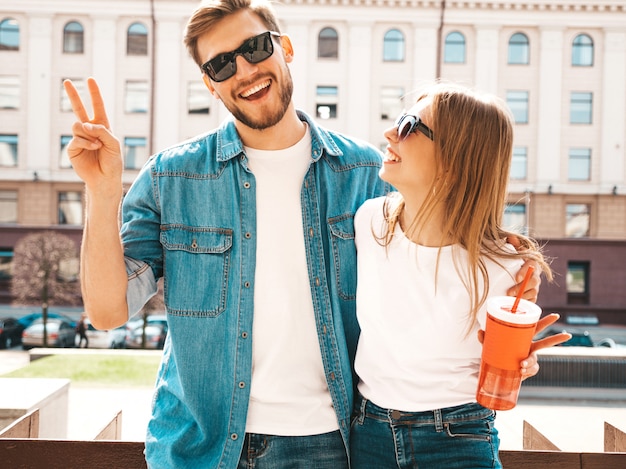 Retrato de menina bonita sorridente e seu namorado bonitão em roupas de verão casual. . com garrafa de água e palha Foto gratuita