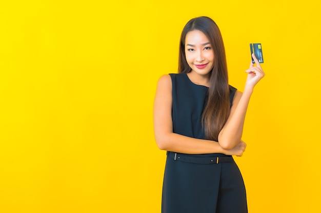 na imagem  uma mulher de negócios jovem com cartão de crédito em fundo amarelo  | O Guia do Cartão de Crédito 